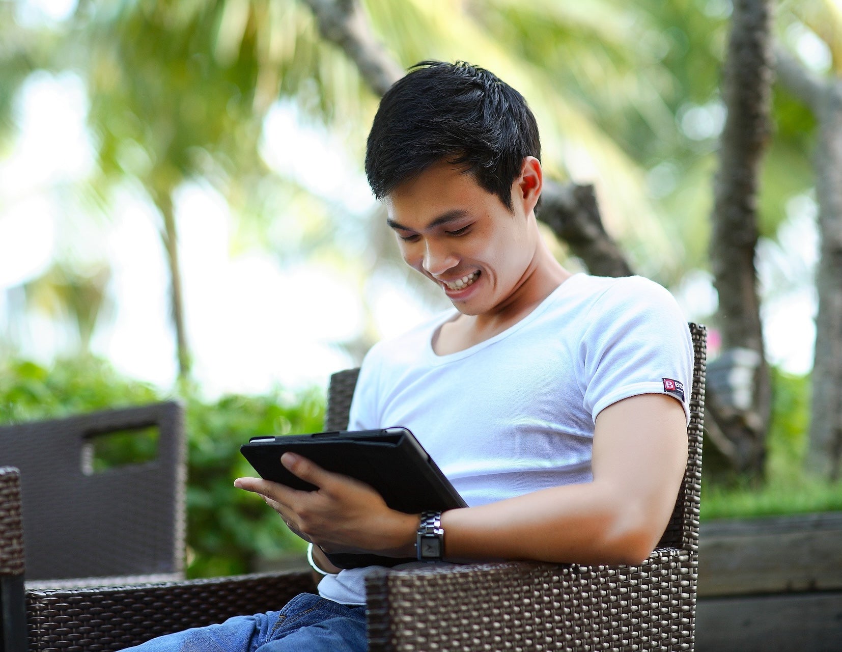 Man using a tablet outdoors in a garden setting